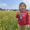 Child model in a field of buttercups wearing turquoise taggle chew necklace with infinity lanyard