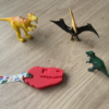 Red dinosaur chew necklace on dinosaur lanyard with toy dinosaurs