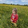 Child in a field wearing a Foot Chew Necklace with rainbows lanyard