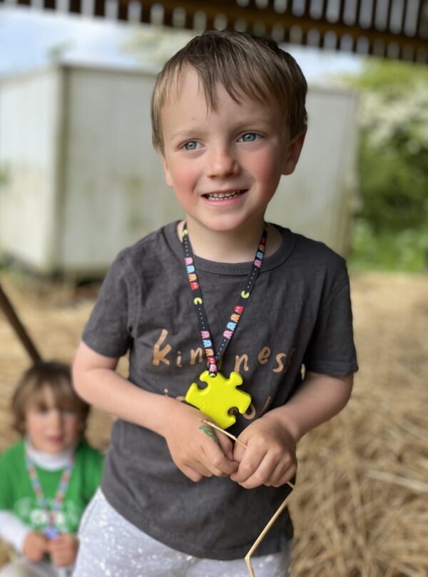 child model wearing yellow puzzle chew necklace on pacman lanyard