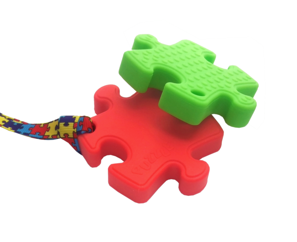 Red puzzle chew and green puzzle chew necklace in a stack
