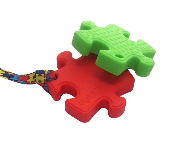 Red puzzle chew and green puzzle chew necklace in a stack