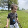 child model wearing star tag sensory chew necklace in a field