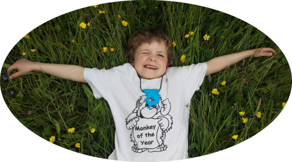Child lying in grass wearing blue shark chew necklace