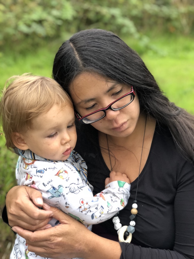 calmer parent mother and toddler having a cuddle, looking at something together